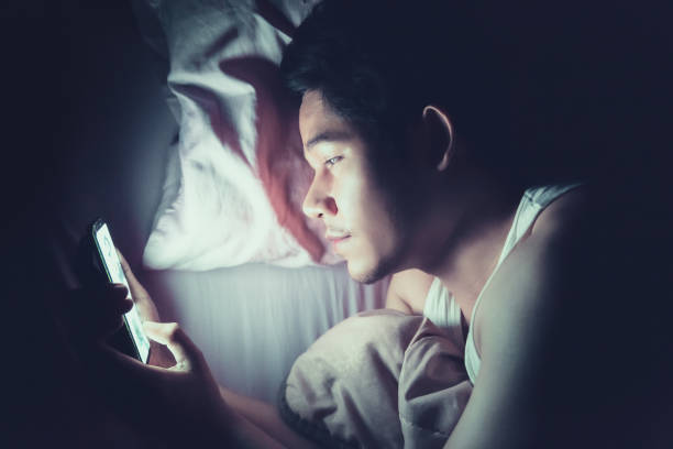 istock Looking at the smartphone screen at night on the bed before sleep 1180036808