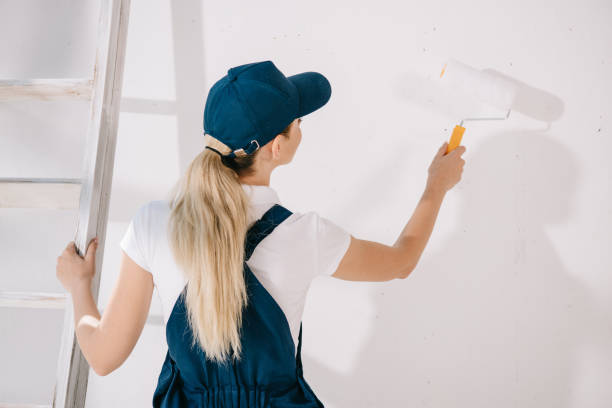istock back view of young painter in uniform standing near white wall and holding paint roller 1180038323