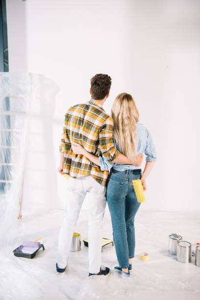 istock back view of young couple embracing while looking at white wall at home 1180038388