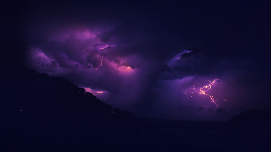 beautiful lightning during a thunderstorm at night in a forest that caused a fire, against a dark sky with rain