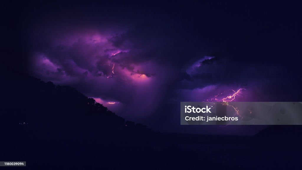 Lightning storm at night. Storm above mountains. Rocky coastline, multi colored Lightning Stock Photo