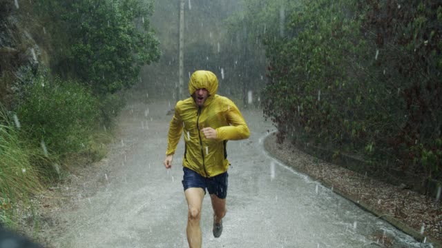 Athletic man jogging in extreme weather condition. Hail and rain