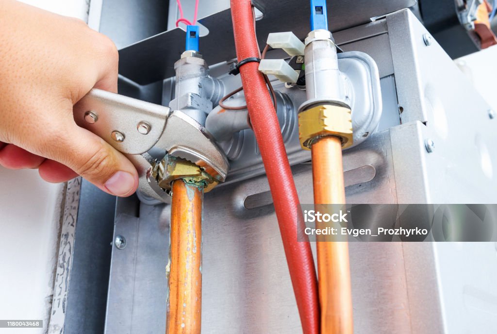 Plumber repairing a gas boiler of a heating home system in the boiler room. Close-up, selective focus. Gas Stock Photo