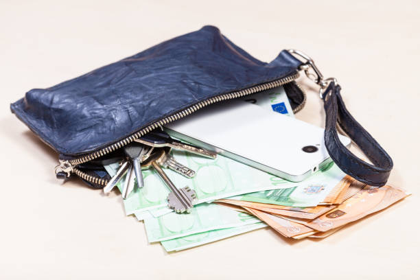 istock handbag with phone, keys and many euros on table 1180045508