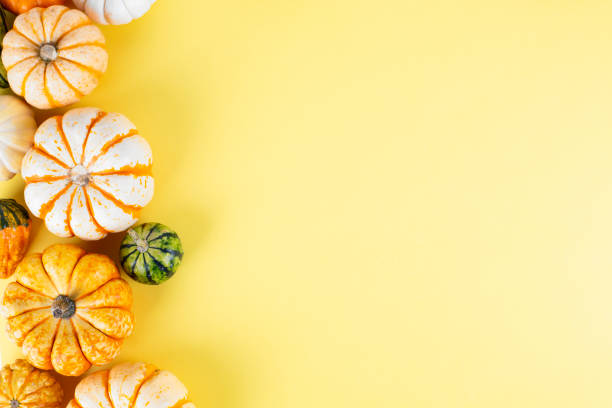 istock Small decorative pumpkins on yellow background 1180049451