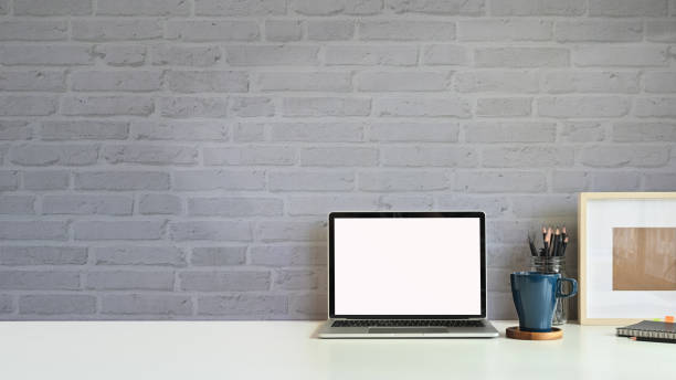 istock Copy space mockup laptop, coffee mug, pencil with photo frame on workspace desk brick wall. 1180053791