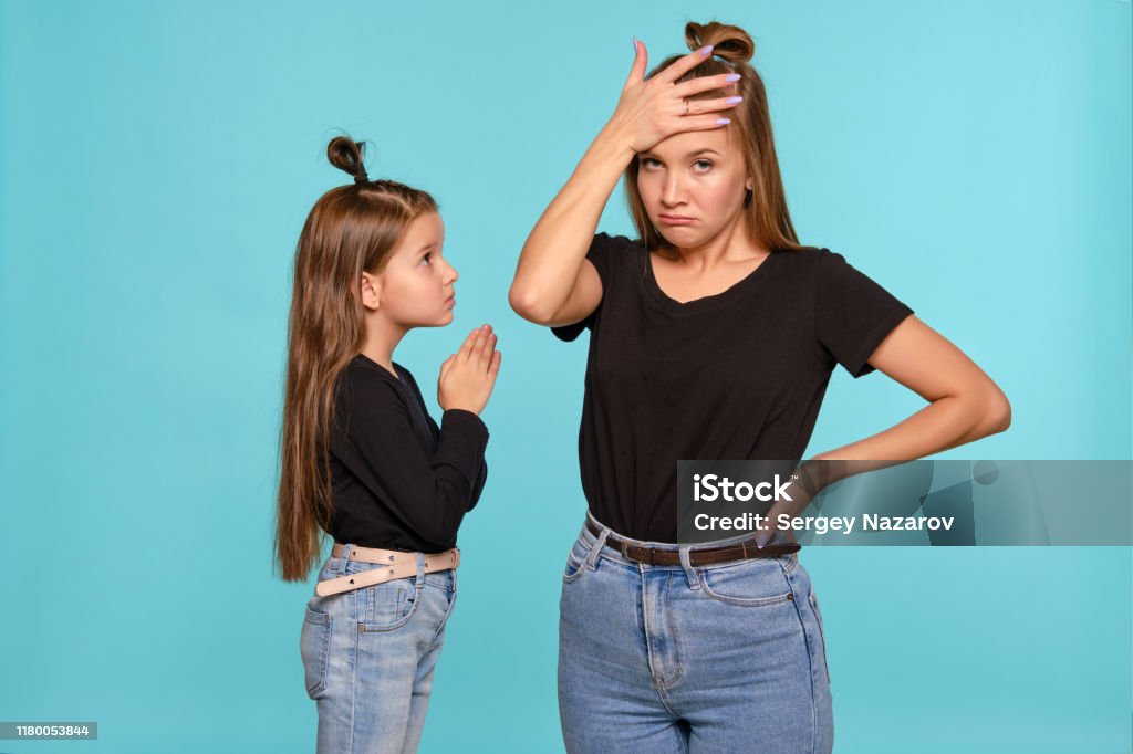 Mom And Daughter With A Funny Hairstyles Dressed In Black Shirts And Blue Denim Jeans Are Posing Against A Blue Studio Background Closeup Shot Stock Photo - Download Image Now - iStock Mom And Daughter With A Funny Hairstyles Dressed In Black Shirts And Blue Denim Jeans Are Posing Against A Blue Studio Background Closeup Shot Stock Photo - Download Image Now - iStock