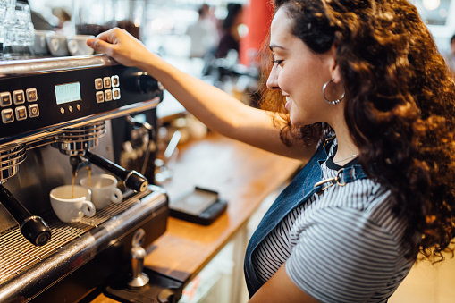 Female barista making coffee with professional coffee maker