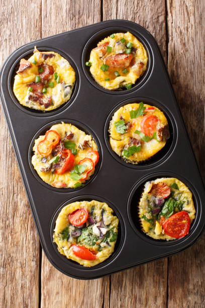istock Breakfast egg muffins with bacon, tomatoes, spinach and mushrooms close-up in a baking dish. Vertical top view 1180054032