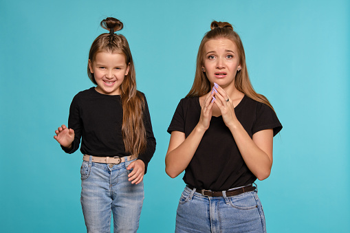 Mom And Daughter With A Funny Hairstyles Dressed In Black Shirts And Blue Denim Jeans Are Posing Against A Blue Studio Background Closeup Shot Stock Photo - Download Image Now - iStock Mom And Daughter With A Funny Hairstyles Dressed In Black Shirts And Blue Denim Jeans Are Posing Against A Blue Studio Background Closeup Shot Stock Photo - Download Image Now - iStock