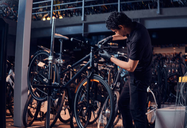 istock Diligent young mechanic is repairing customer's bicycle at workplace 1180055435