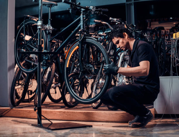 istock Expirienced young master is repairing customer's bicycle at workplace 1180056850