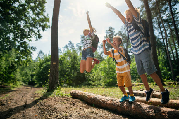 istock Little hikers jumping off tree trunks  in forest 1180058349