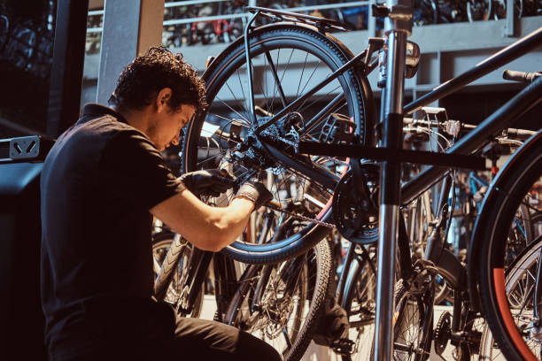 istock Attractive mechanic is fixing customer's bicycle at his own workshop. 1180058698
