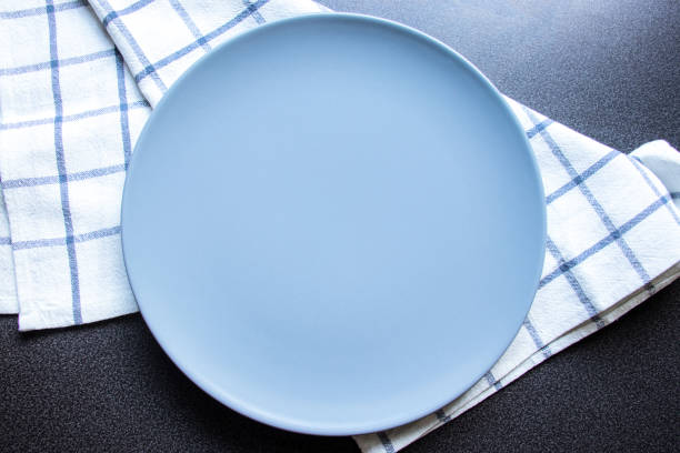 istock Plate, kitchen towel. Empty blue plate and a kitchen towel on a grey stone background. A place for your design. 1180060140