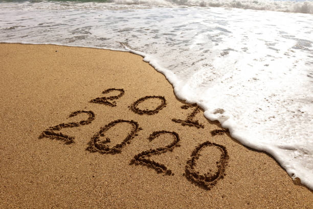 istock New year 2020 and 2019 on sandy beach with waves 1180060690