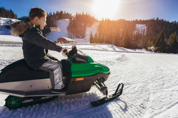 istock Boy driving snowmobile in a winter landscape 1180061411