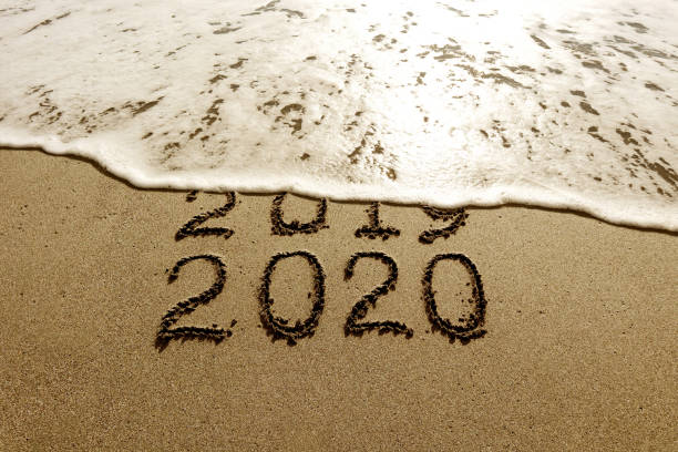 istock New year 2020 and 2019 on sandy beach with waves 1180064022