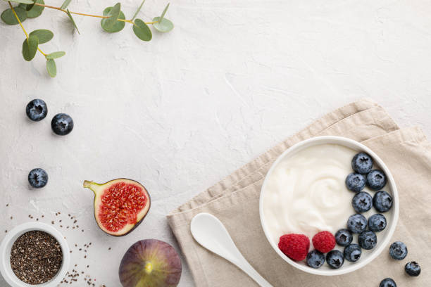 White fermented yogurt with blueberry, figs, chia seeds and raspberry in bowl on light gray table natural healthy superfood fermented yogurt with blueberry, figs, chia seeds and raspberry in white  bowl on light gray table. Image is copy space and top view yoghurt stock pictures, royalty-free photos & images