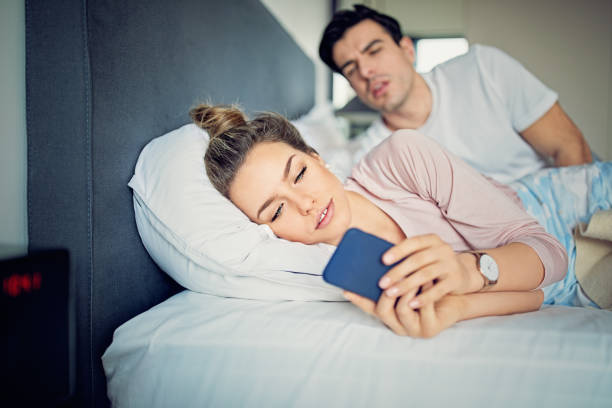 istock Jealous husband is peeking his texting wife in the bed 1180066741