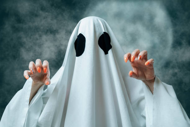 istock White ghost with spooky gesture in Halloween full moon night. 1180069679