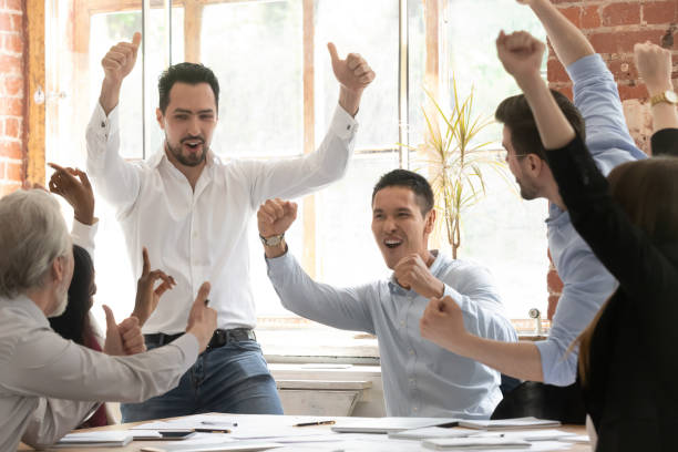 istock Excited diverse colleagues celebrate team win in office 1180069941