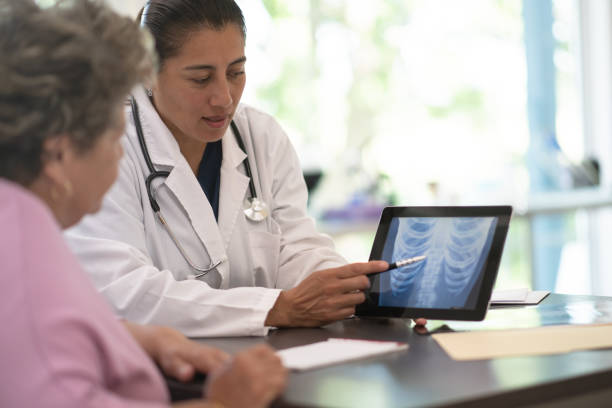 Woman Receiving X-ray Results from the Doctor stock photo Older woman receiving and reviewing her x-ray results from the doctor osteoporosis stock pictures, royalty-free photos & images