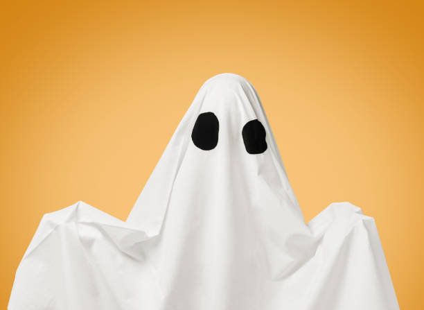 istock White ghost with black eyes on yellow background. 1180071046