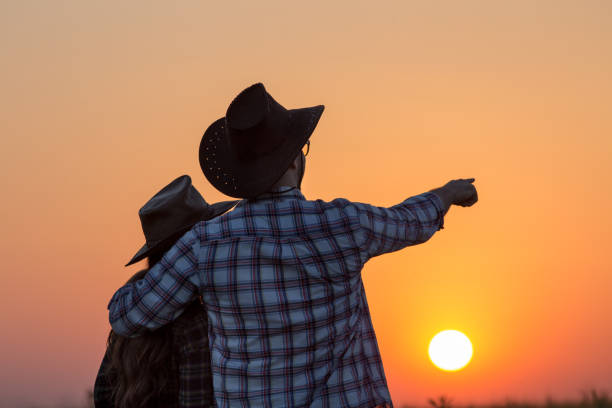 istock Couple with hats looking at sunset 1180074081