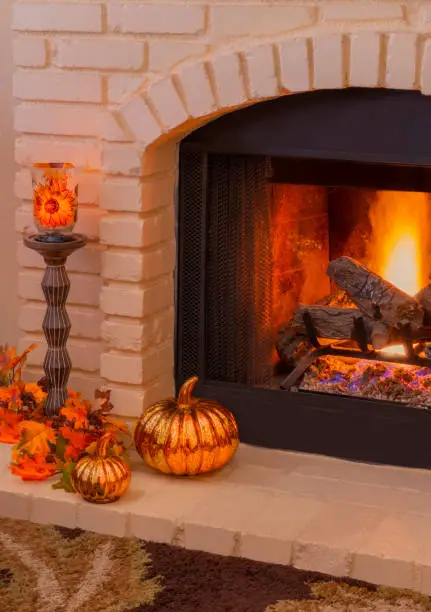 Photo of Brick fireplace with fall decorations and burning logs (P)