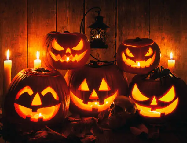 Halloween Jack-o-Lantern Pumpkins on rustic wooden background