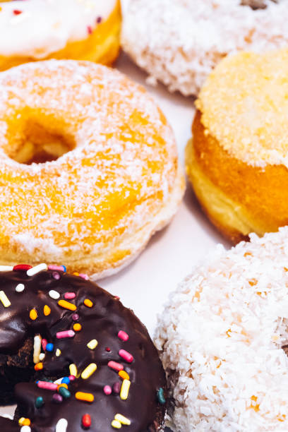 istock Assorted multicolored donuts in a bakery box with chocolate frosted, glazed and sprinkles donuts. Sugar addiction or festive menu concept. 1180078470