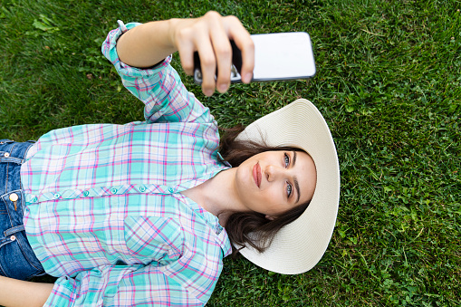 Beautiful young Caucasian woman with selfie with smartphone outdoors in park