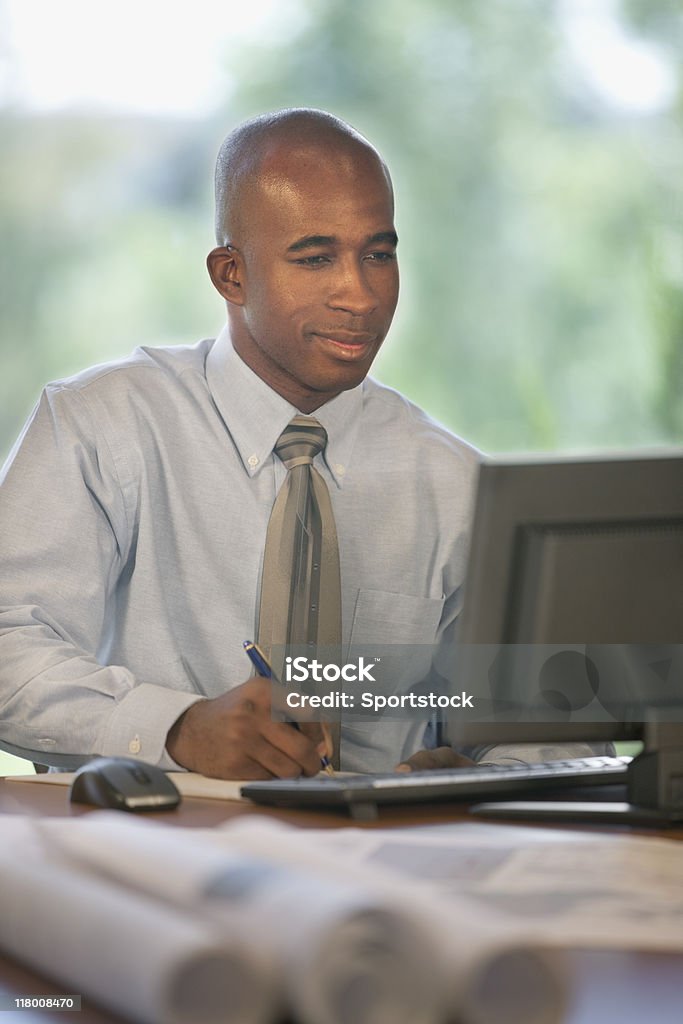 Przystojny czarny człowiek pracy na komputerze - Zbiór zdjęć royalty-free (Biurko)
