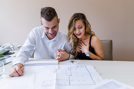 Smiling young married couple watching project of their new apartment. Home investment '