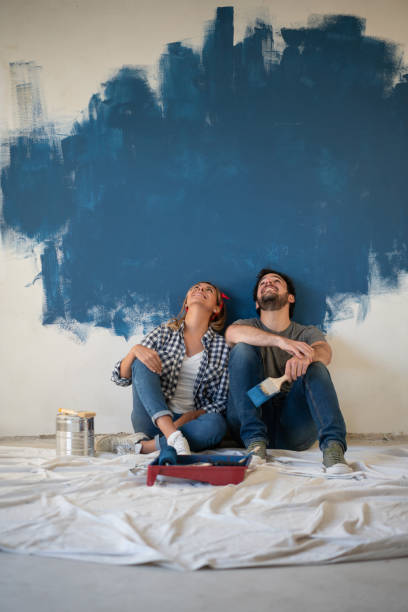 thoughtful couple taking a break from painting their house - home addition home improvement paint decorating imagens e fotografias de stock