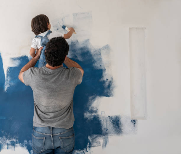 ragazzo che aiuta suo padre a dipingere la casa - home addition home improvement paint decorating foto e immagini stock