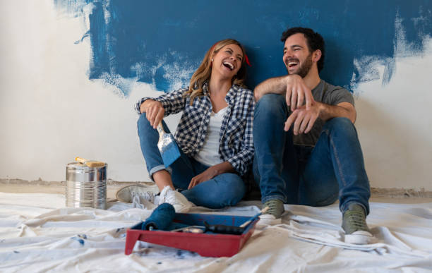 istock Happy couple laughing while painting their house 1180089721