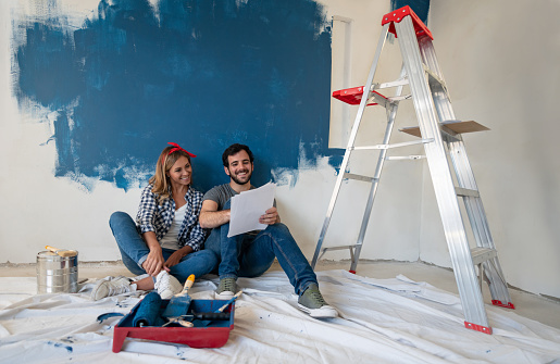 Portrait of a loving young couple looking very happy painting their house and smiling - home improvement concepts