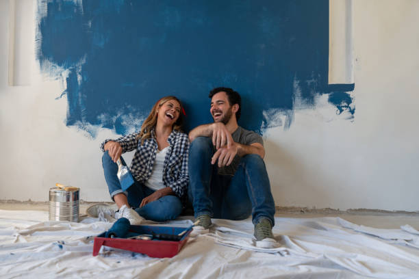 couples heureux riant tout en prenant une pause de la peinture - redecoration photos et images de collection