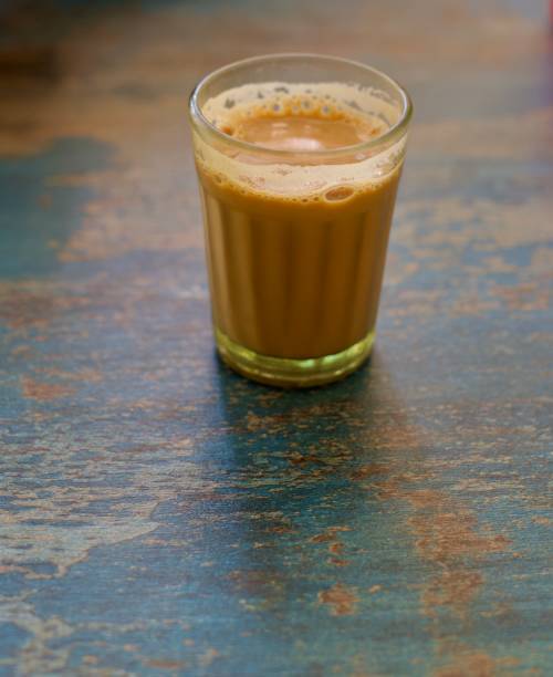 Indian/Asian Masala Chai / Milk Tea in tiny glass Freshly brewed Indian/Asian Masala Chai/Milk Tea in tiny glass kept on wooden table chai stock pictures, royalty-free photos & images