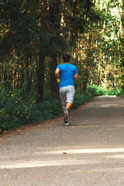 istock Young active handsome male healthy runner jogging outdoors along a scenic path in a forest. Vertical shot. 1180106621