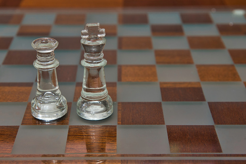 King and Queen pieces side by side on a chess board