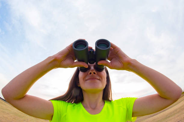 istock girl in a yellow jacket looking through binoculars against the sky 1180112406