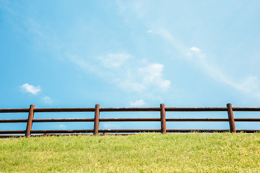 Wooden fence and green grass field with blue sky