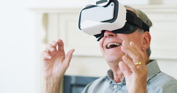 Shot of happy senior man using a virtual reality headset at home