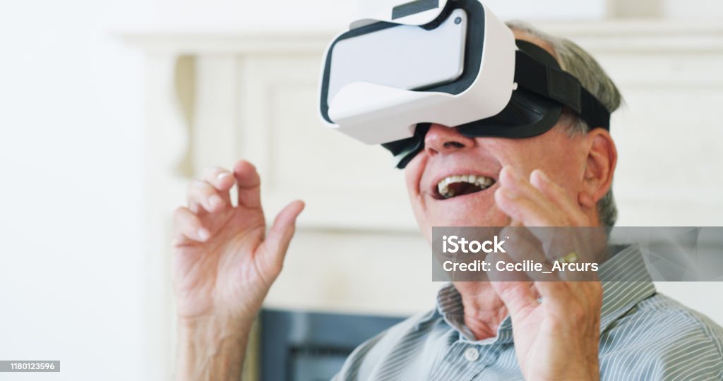 It's the stuff you find in your fantasies Shot of happy senior man using a virtual reality headset at home Virtual Reality Simulator Stock Photo