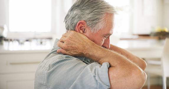 Shot of a senior man experiencing shoulder pain at home