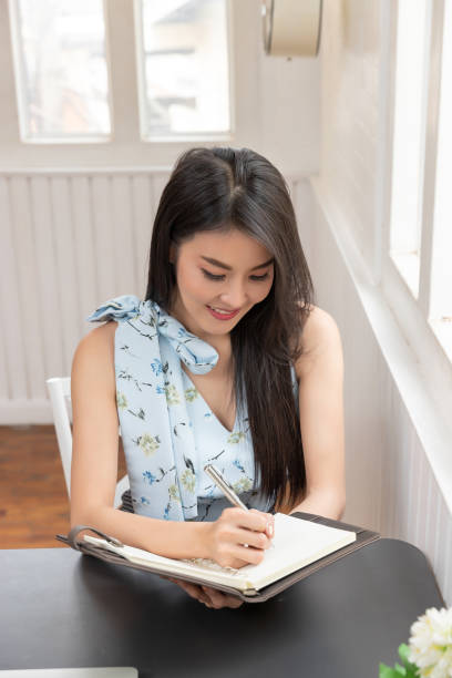 istock Freelancer business woman  working and writing on notebook in cafe. 1180129809