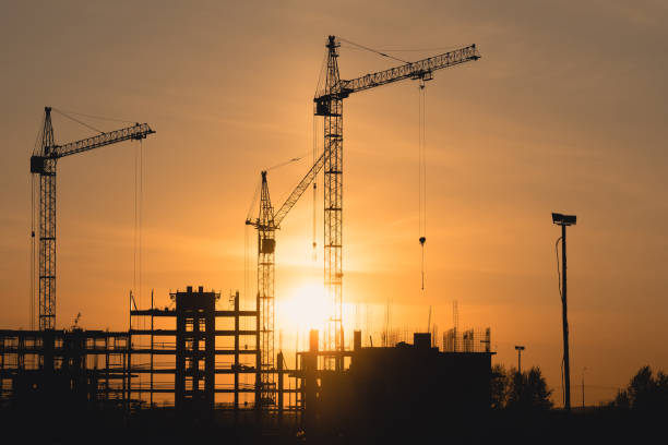istock silhouettes of construction cranes at sunset 1180131557